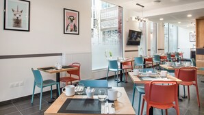 Un comedor moderno con varias mesas y sillas, cuadros en las paredes y un ventanal que proporciona luz natural.
