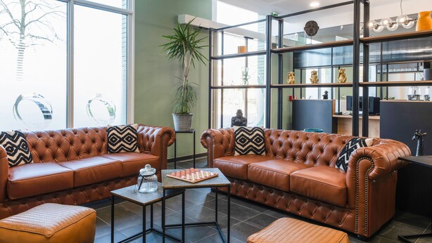 Una sala moderna con sofás de cuero, una mesa de centro y una planta en maceta.