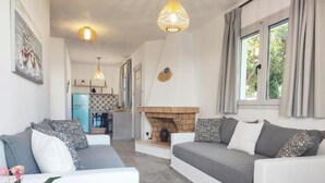 Un salon moderne avec un ensemble de canapés, une cheminée et une cuisine en arrière-plan.