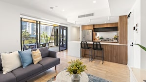 A modern apartment with a living area, kitchen, and large windows overlooking a cityscape. - The Monterey Apartments by Urban Rest (Kangaroo Point)