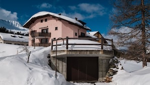 A pink chalet with a balcony, surrounded by snow-covered mountains. - Haus Sunneschy Whg. 202 by Interhome (Parpan)
