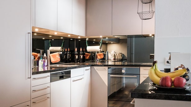 A modern kitchen with white cabinets, a black countertop, and a wooden floor. - Haus Sunneschy Whg. 202 by Interhome (Parpan)