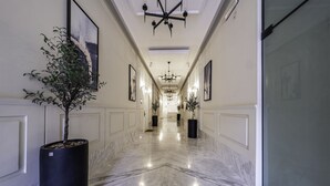 A marble-floored hallway with potted plants, framed artwork, and a chandelier. - Mabaat - Al Malqa - 543 (Riyadh)