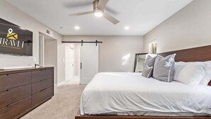 Une chambre d’hôtel moderne équipée d’un lit, d’une commode, d’une télévision et d’un ventilateur de plafond.