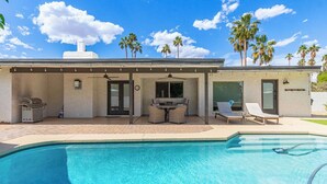 Une maison moderne dotée d’une piscine, d’un espace salon extérieur et de palmiers.