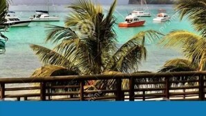 A tropical beach scene with boats and palm trees. - Villa Des Quatre Saisons (Pereybere)