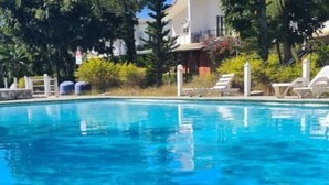 A swimming pool with lounge chairs and a building in the background. - Villa Des Quatre Saisons (Pereybere)