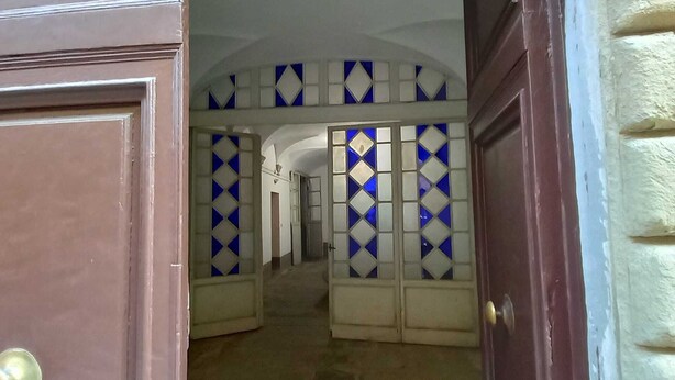 A hallway with a patterned wall and a wooden door. - Sosia Palace, Pisa (Pisa)