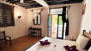 Quarto de hotel com uma cama, uma escrivaninha e uma cadeira.