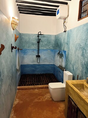Ein Badezimmer mit blauen und braunen Farbtönen, einer Dusche, einer Toilette und einem Waschbecken.