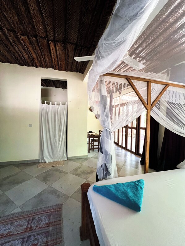 A room with a bed, a wooden bench, a table, and a chair.