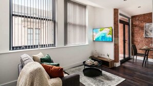 A living room with a sofa, a coffee table, and a TV mounted on the wall.