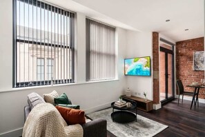 A living room with a sofa, a coffee table, and a TV mounted on the wall.
