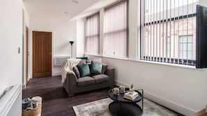 A modern living room with a sofa, a coffee table, and a window with blinds.
