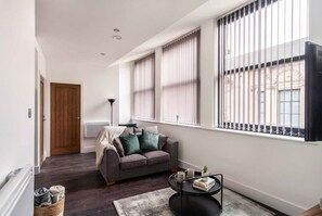 A modern living room with a sofa, a coffee table, and a window with blinds.