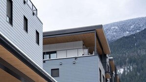 A modern multi-story building with a flat roof and a balcony. - Epic Mountain Views & AC | 2.5km to RMR & Town⁠ (Revelstoke)