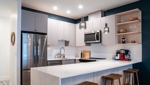 A modern kitchen with a large island, stainless steel appliances, and wooden bar stools. - Epic Mountain Views & AC | 2.5km to RMR & Town⁠ (Revelstoke)