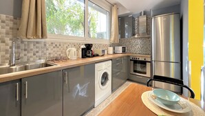 Een moderne keuken met roestvrijstalen apparatuur, een ingebouwde wasmachine en een raam met gordijnen.