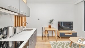 A modern kitchen with a Bosch range hood, a toaster, a kettle, and a wooden dining table with a TV. - Studio With City Views (Cape Town)