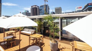 A rooftop terrace with outdoor seating, potted plants, and a view of the city skyline. - Studio With City Views (Cape Town)