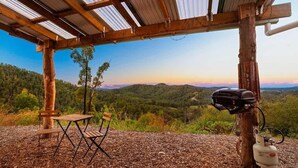 Un espace extérieur aménagé avec une table et des chaises, un barbecue et une bouteille de propane.