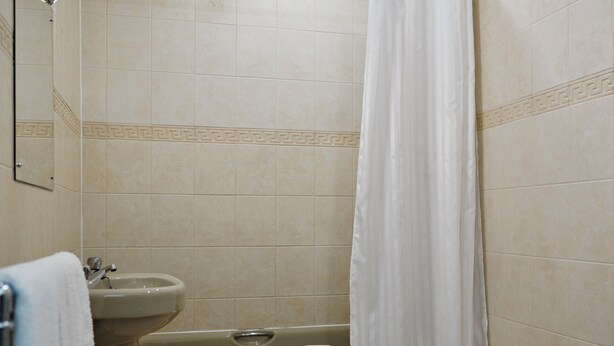 A bathroom with a bathtub, sink, and toilet. - Hotel Ambassadeur (St. Clement)