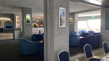 A modern restaurant with blue seating, white brick walls, and a fireplace.