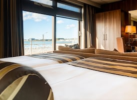 Habitación de hotel con una cama grande, un sofá, un escritorio y vistas al mar.