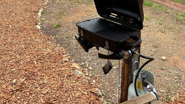 Grilli on sijoitettu puisen rakenteen alle, ja sieltä avautuu näkymä metsään ja kaukaisiin kukkuloihin.