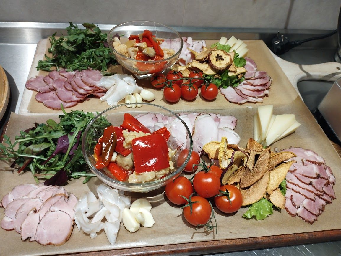 Tábua de frios com diversos tipos de carne, queijos e vegetais.