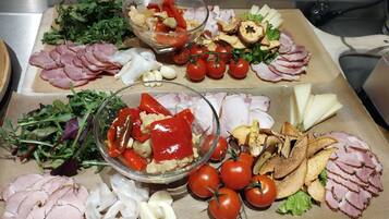 Tábua de frios com diversos tipos de carne, queijos e vegetais.