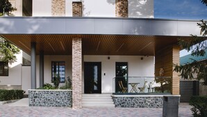 A modern building with a covered entrance, stone steps, and outdoor seating. - ECODOR HOTEL (Orhei)