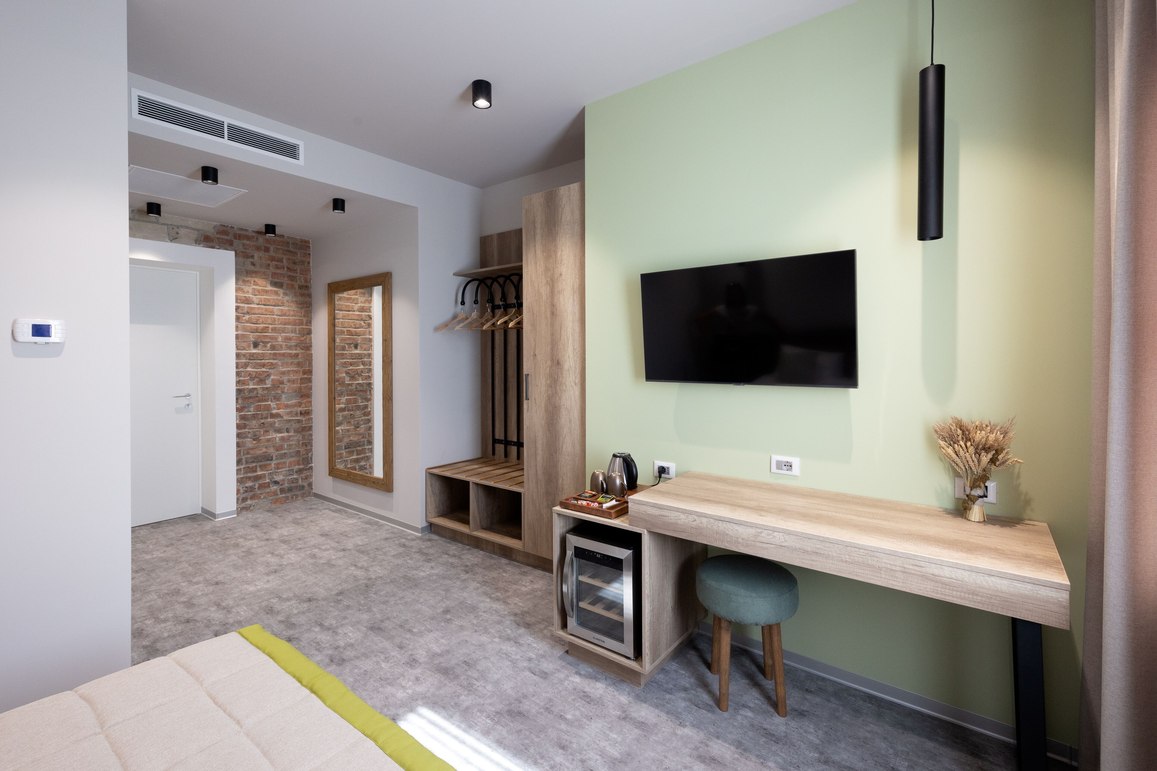 A modern room with a TV, a desk, a coffee machine, and a wardrobe.