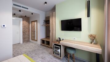 A modern room with a TV, a desk, a coffee machine, and a wardrobe.