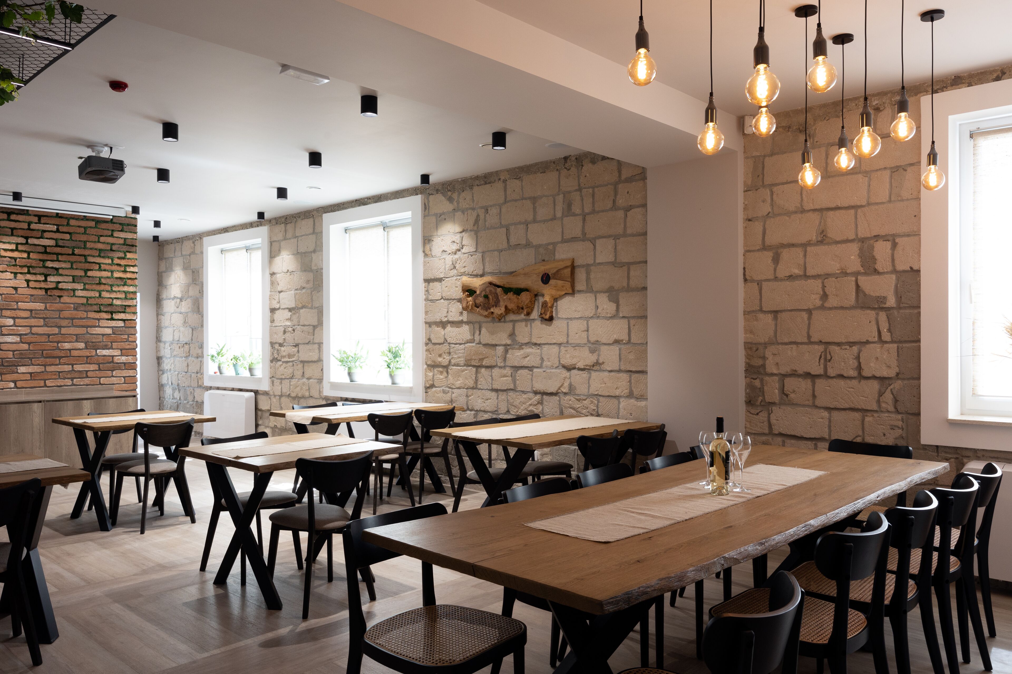 Un comedor moderno con paredes de ladrillo, mesas de madera y sillas negras.