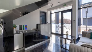 En moderne hotellobby med en stilfuld trappe, et glasbord og en sofa.