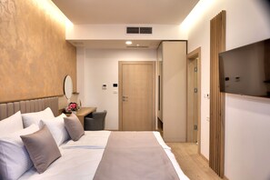 A hotel room with a bed, bedside table, mirror, and a TV. - Hotel Emerald (Mostar)