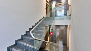 En moderne trappe med glasgelændere og håndskinne, der fører til en elevator.
