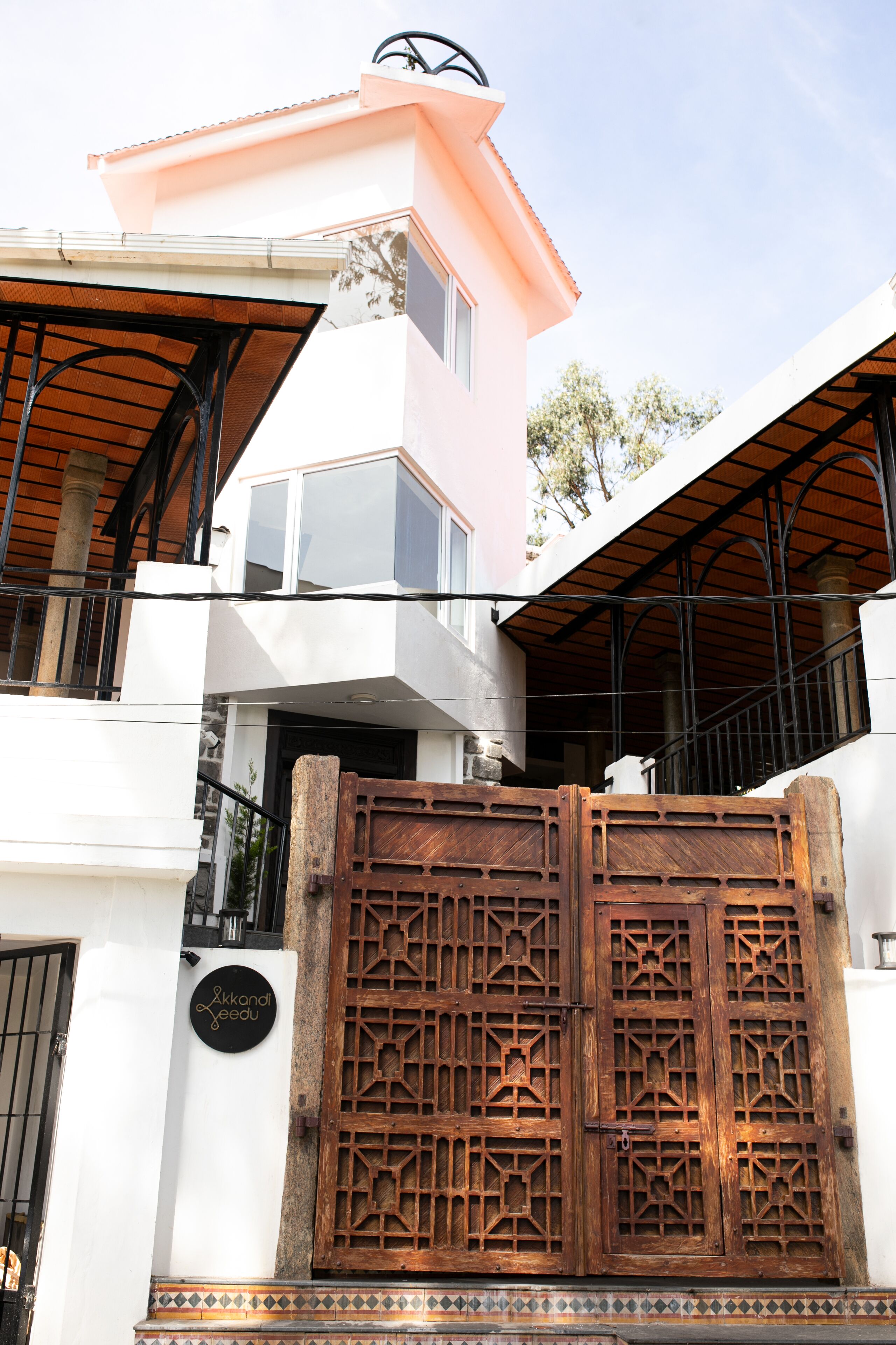 A building with a white facade, a balcony, and a large wooden gate.