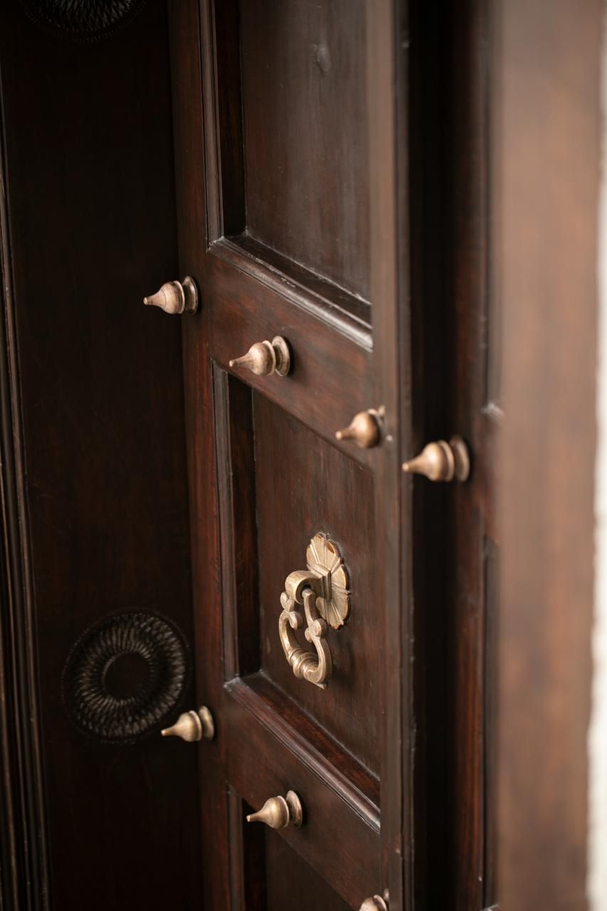 Une porte en bois, dotée de poignées en laiton et d’un trou de serrure décoratif.