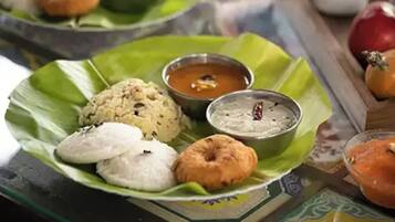 A plate of food with idlis, dosas, and chutneys on a banana leaf.