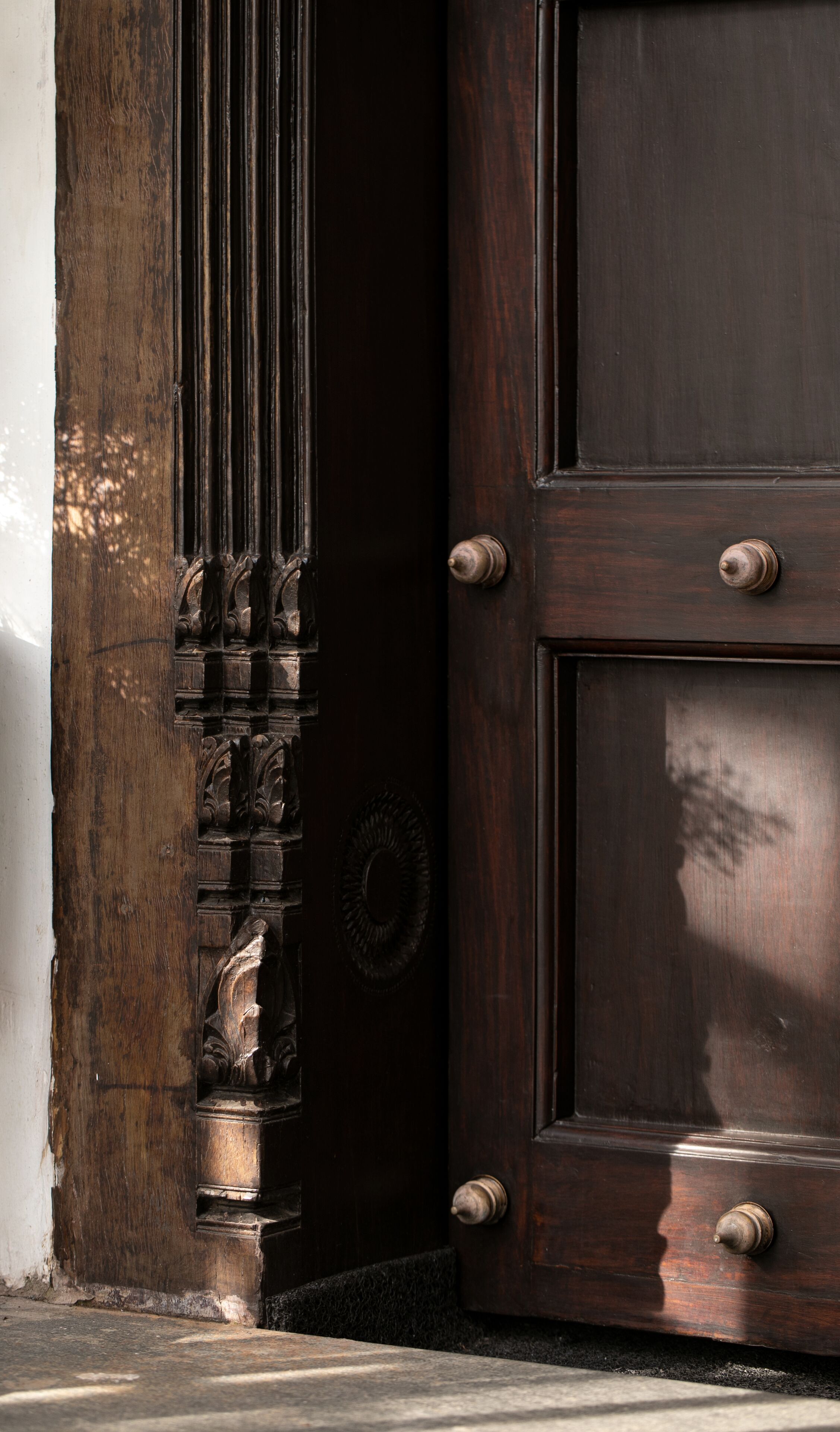 Una puerta de madera oscura con tallas intrincadas y un pomo redondo.