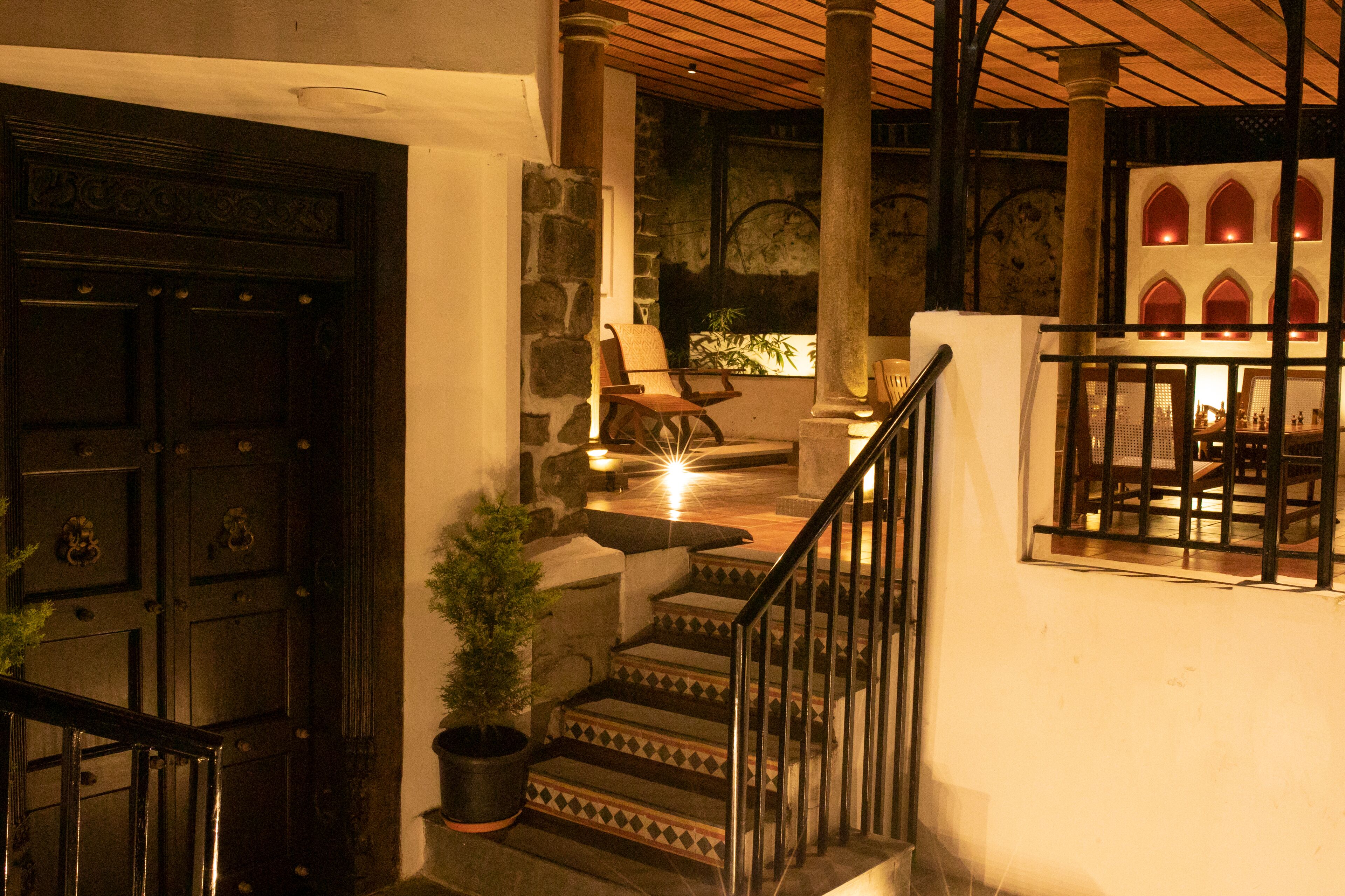 A staircase with a metal railing leading to a second-floor area with a dining table and chairs.