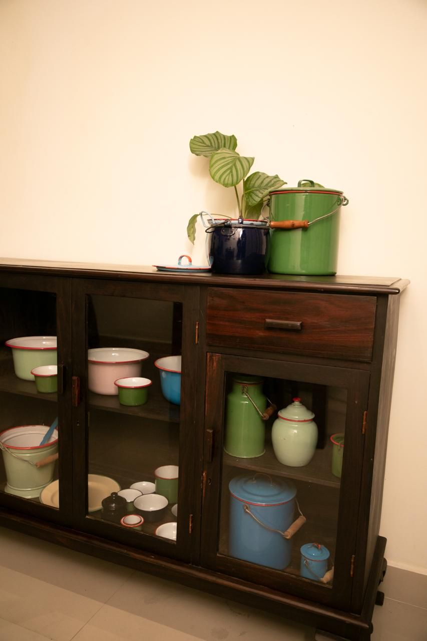 A wooden cabinet with glass doors containing various kitchenware.
