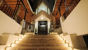 A staircase with patterned tiles leading to a dark door, surrounded by walls and metal railings. - Akkandi Veedu (Kodaikanal)
