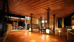 A spacious lobby with a high ceiling, large columns, and a tiled floor. - Akkandi Veedu (Kodaikanal)
