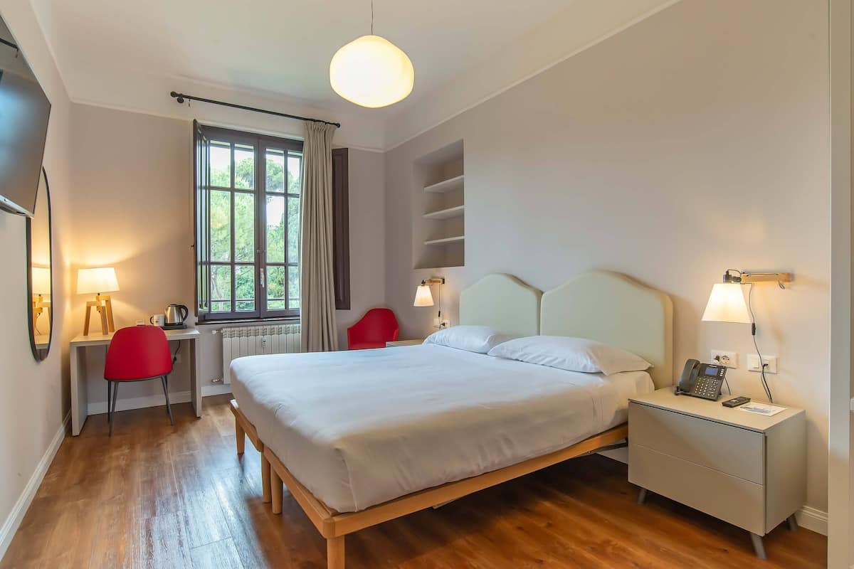 Une chambre bien rangée, avec un lit, des tables de chevet, un bureau et une chaise.