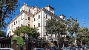 Un edificio de varios pisos con estilo arquitectónico clásico, con ventanas en arco y una fachada simétrica.
