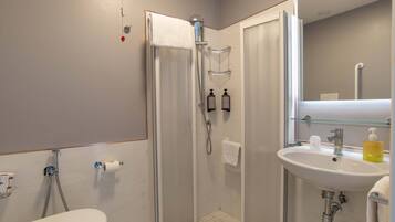 A modern bathroom with a glass-enclosed shower, a white sink, and a toilet.