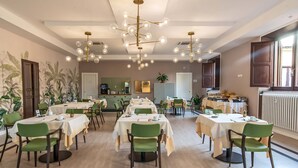 Comedor con varias mesas y sillas, cocina al fondo y techo con una lámpara original.